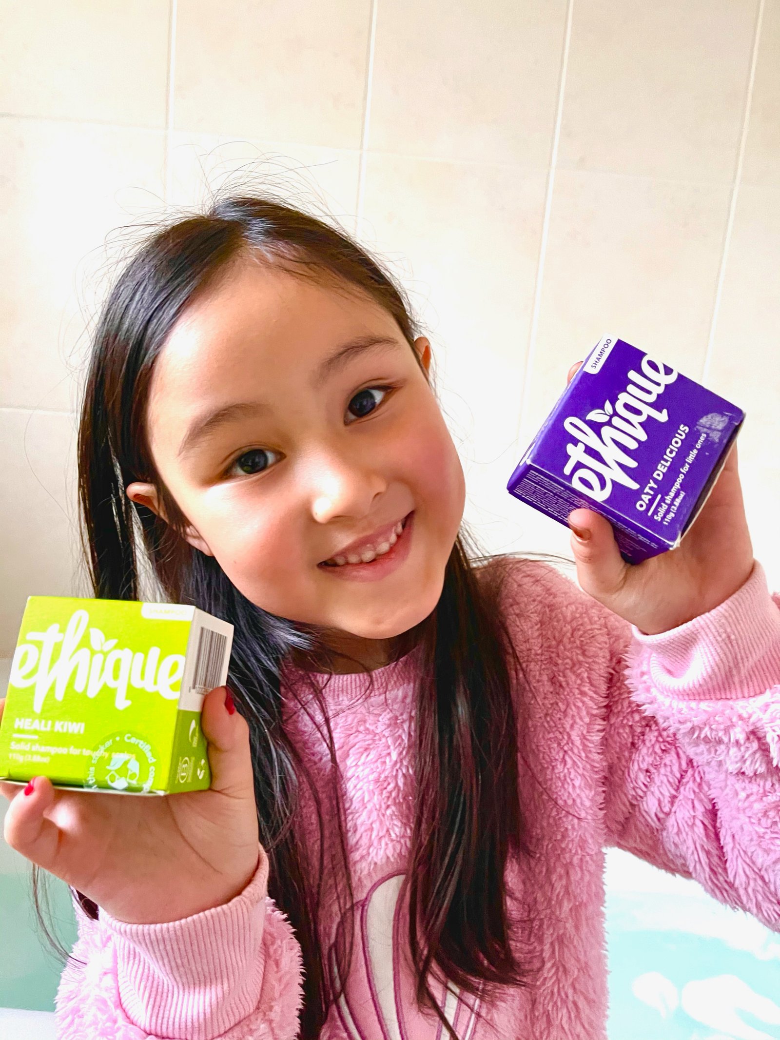 Yasmin showing her Ethique Oaty Delicious kids shampoo bar made with coconut oil, oats and lavender in our bathroom. She is also showing the bright green ethique heali kiwi shampoo bar that I use for my dry scalp.