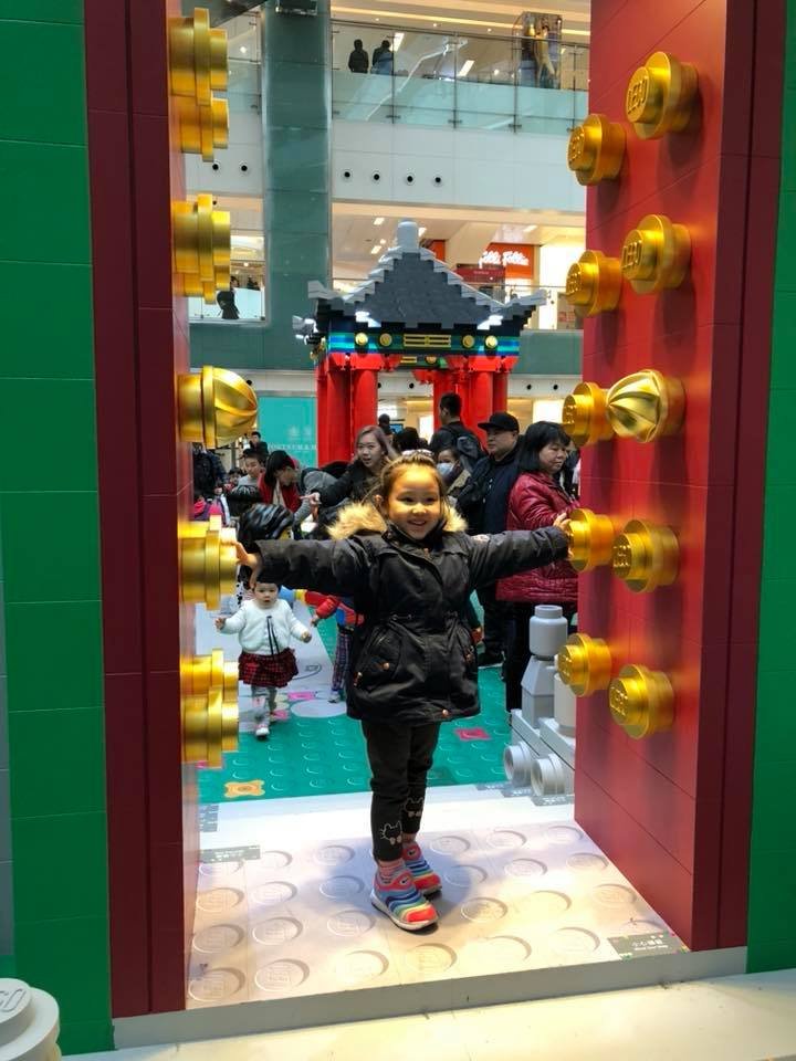 Yasmin standing between large red lego doors with golden studs for chinese new year in Hong Kong 