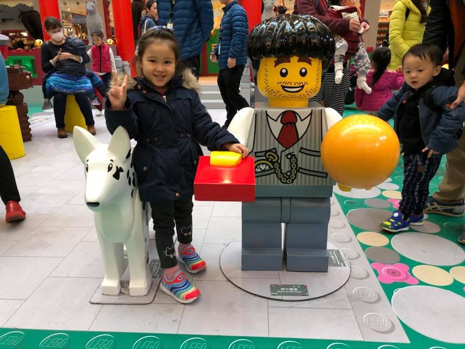 Lego Chinese New Year in New Town Plaza, Sha Tin Hong Kong. Lei Hang daughter posing a lego character holding an orange and a red envelope also known as lucky money and a dog in 2018. Year of the dog