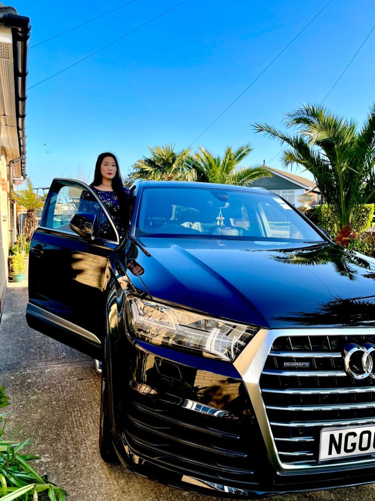 Lei Hang standing in a black Audi Q7 S-line. Could the thrifty island girl give up her car for a £3000 travel credit funded by the government? 