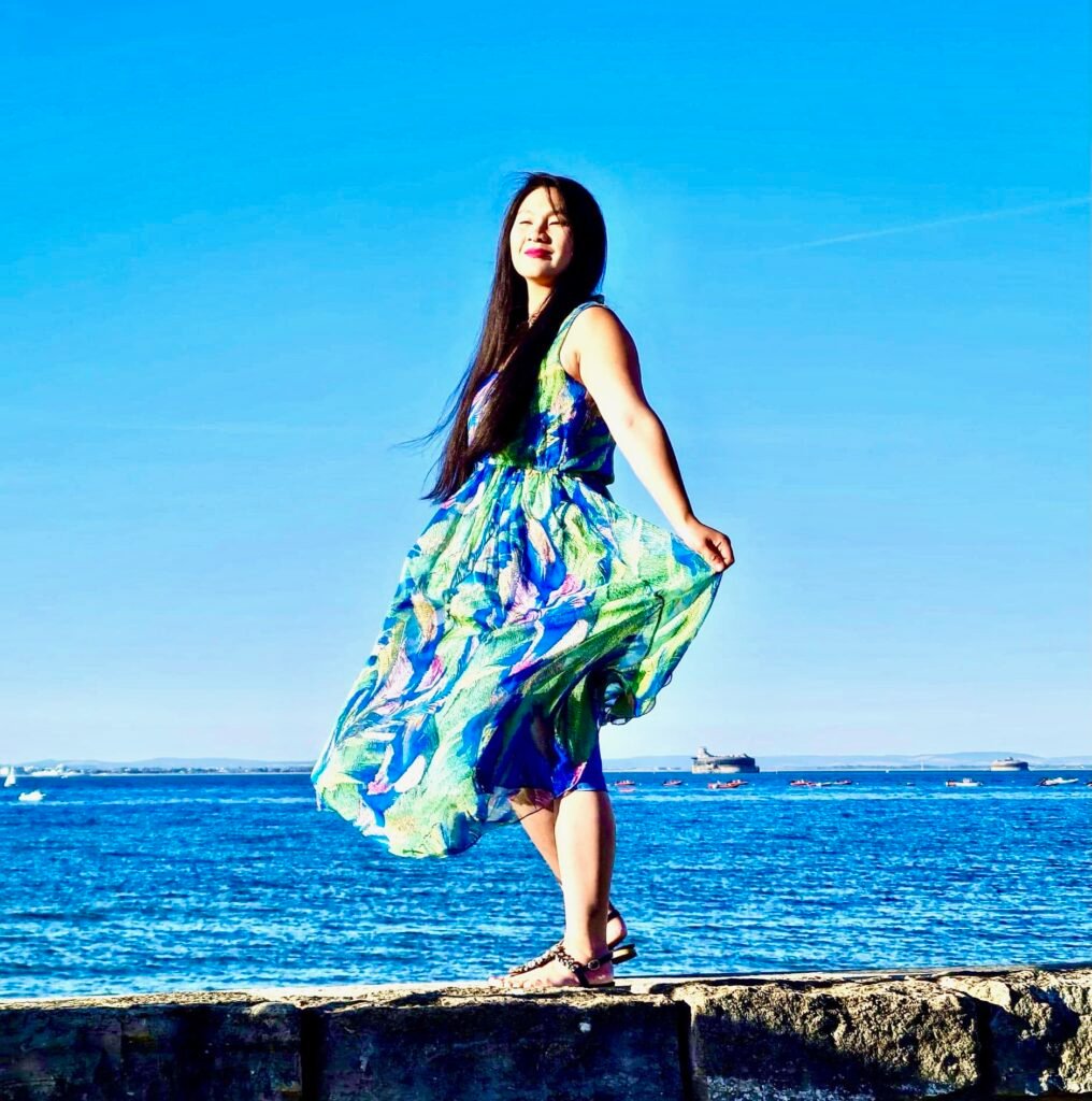Lei Hang wearing a blue green maxi dress at the beach on the Isle of Wight enjoying the sun. While enjoying the sun she wears suncream to protect her skin.