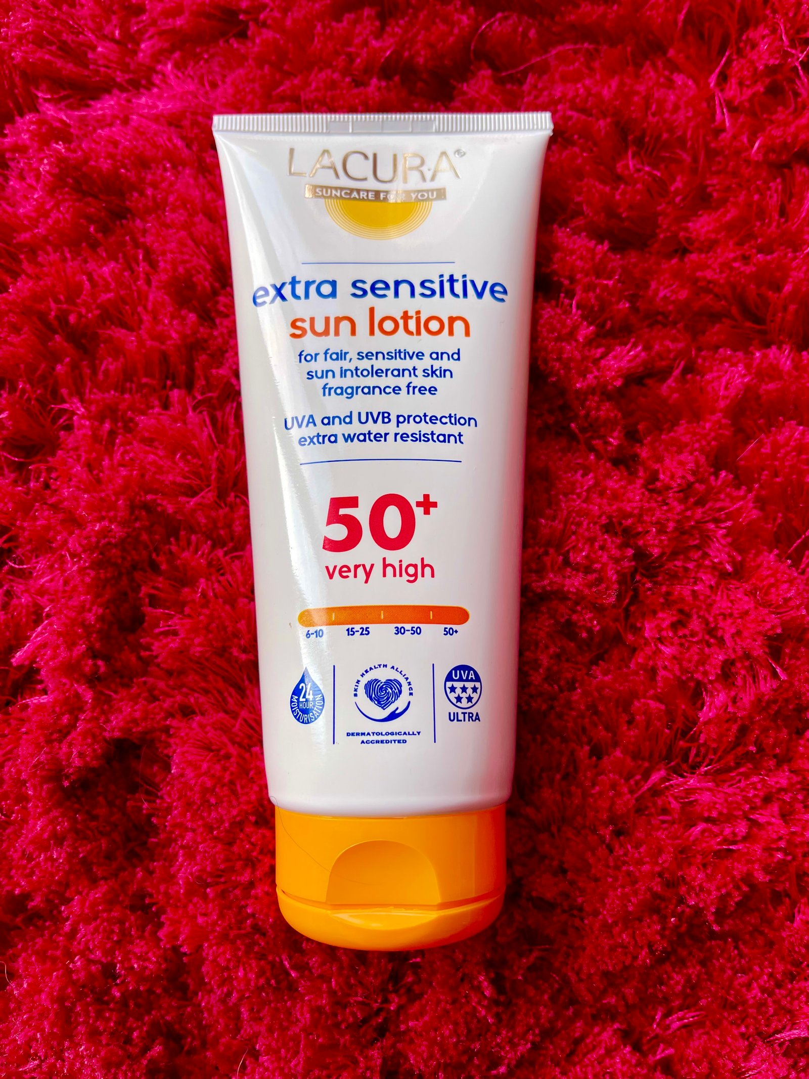 Lacura extra sensitive sun lotion suncream by Aldi on red fluffy background